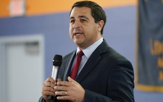 Kaul stands holding a microphone.